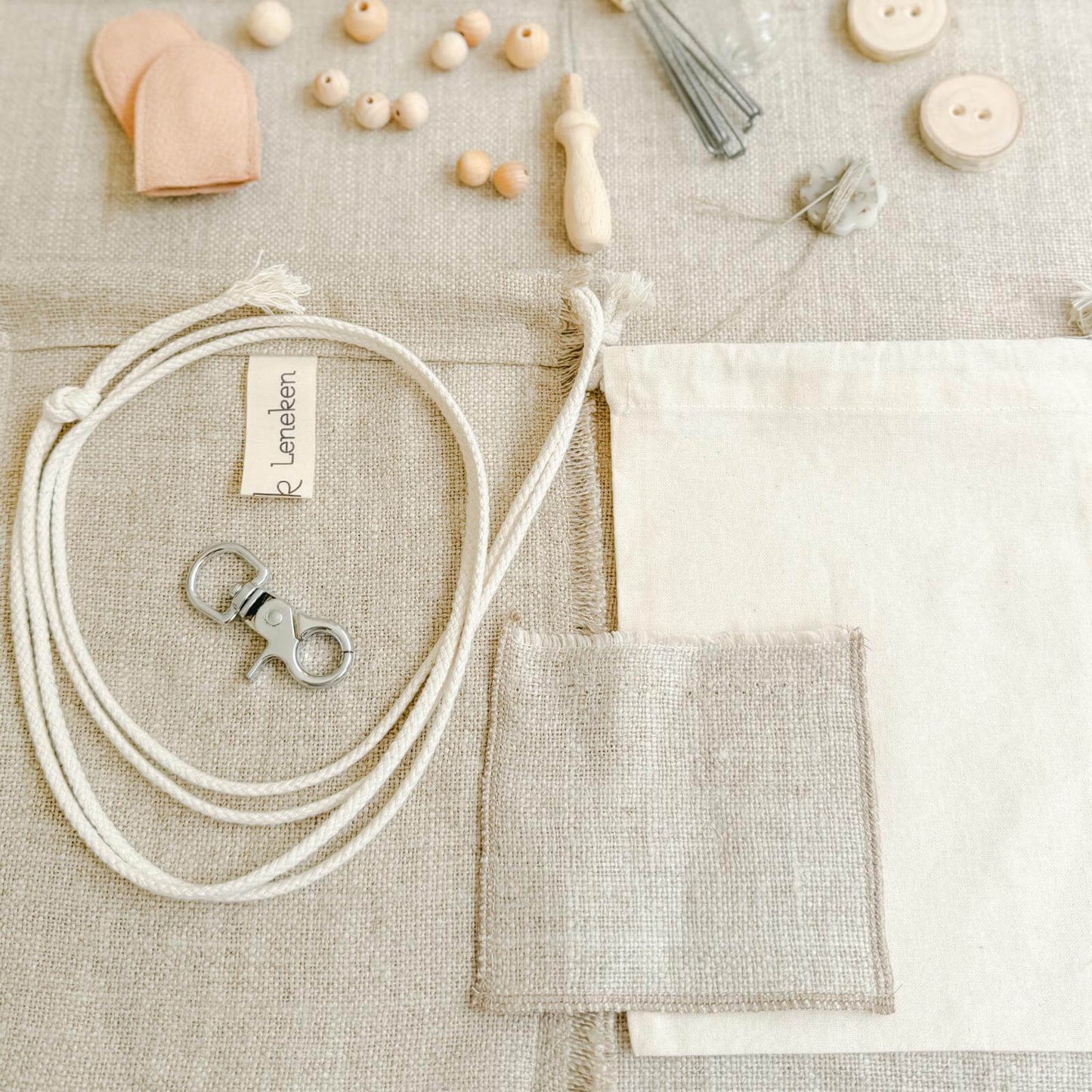 Zubehör und Materialien des Filzsets – Leinen, Filznadel, Holzperlen.