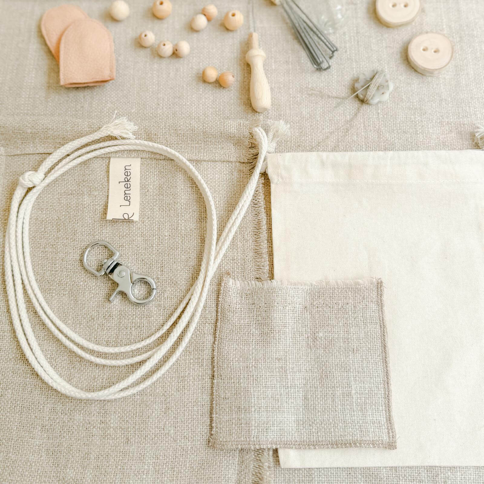 Zubehör und Materialien des Filzsets – Leinen, Filznadel, Holzperlen.