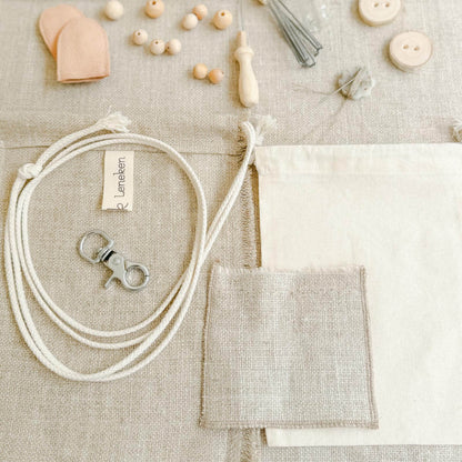 Zubehör und Materialien des Filzsets – Leinen, Filznadel, Holzperlen.