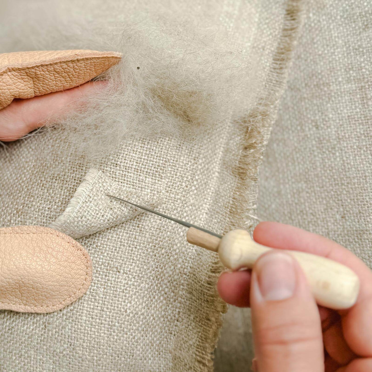 Filzen mit Filznadel auf Leinenbeutel – Detailaufnahme mit Fingerschutz.